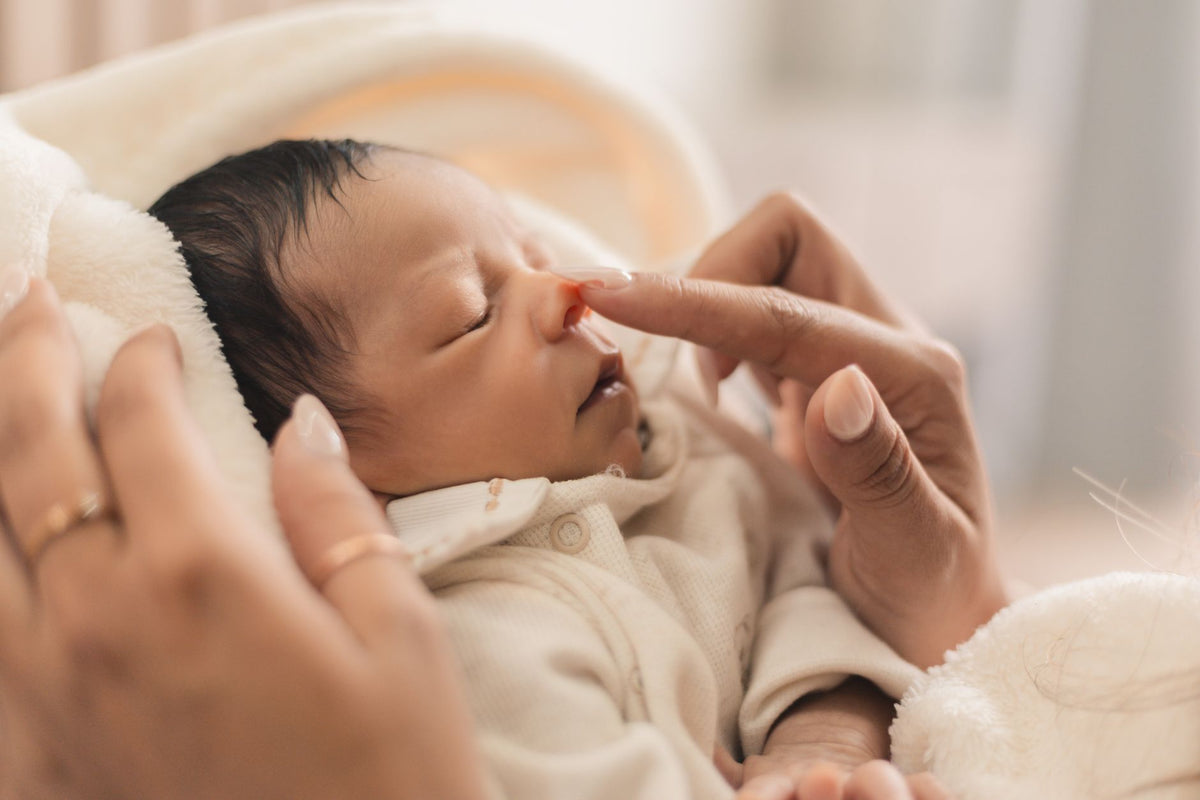 Parent effleurant le nez d'un nouveau-né endormi - mouche-bébé | Petit Murmure