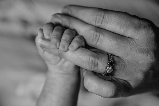 Jeune maman portant un bijou gravé avec son bébé dans les bras | Petit Murmure