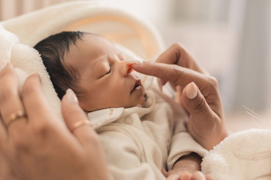 Parent effleurant le nez d'un nouveau-né endormi - mouche-bébé | Petit Murmure